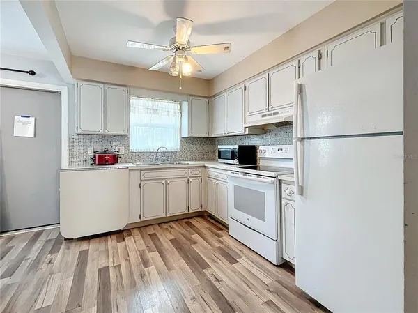 a white kitchen with sink a refrigerator and white cabinets