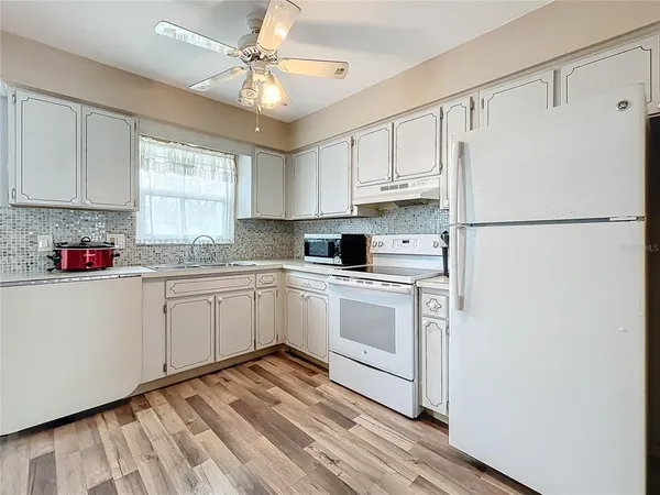 a kitchen with white cabinets white appliances and sink