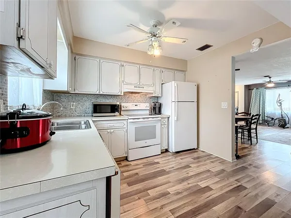 a kitchen with granite countertop a refrigerator a sink dishwasher and white cabinets with wooden floor