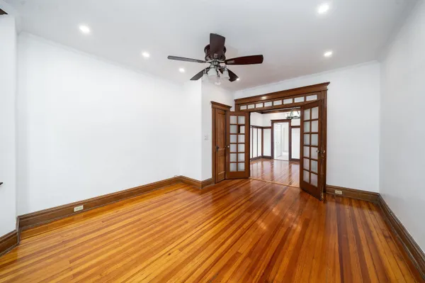 a view of empty room with wooden floor and fan