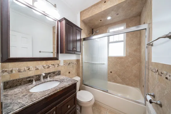 a bathroom with a granite countertop sink a toilet a mirror and shower