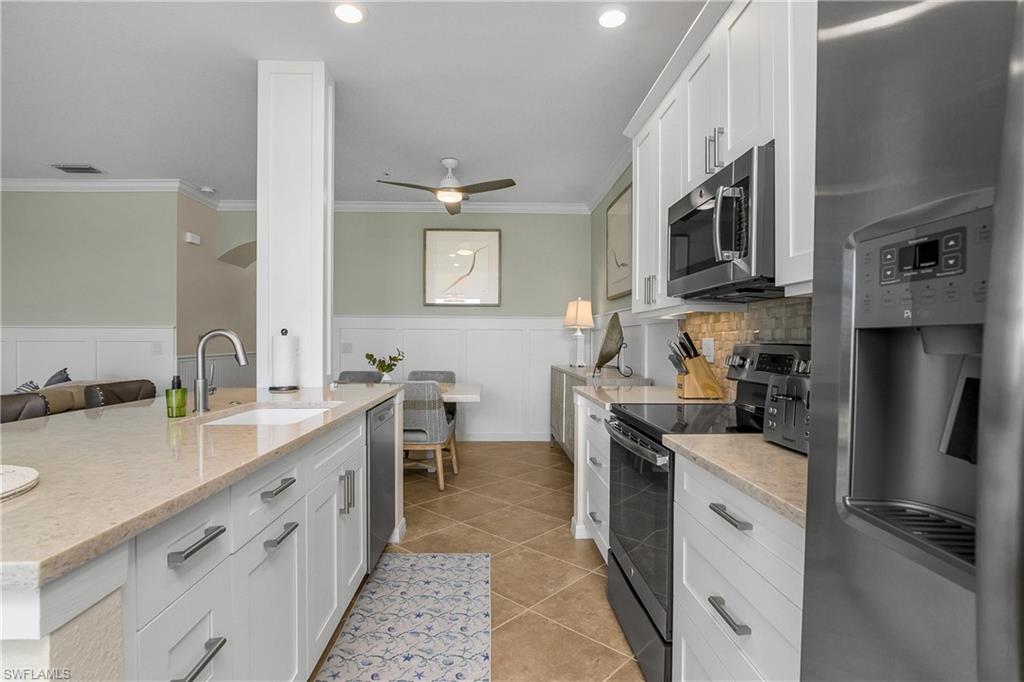 9834 Giaveno Circle, Unit 1746 Naples, FL 34113 - Photo 10 of 41 a kitchen with stainless steel appliances a sink stove refrigerator and cabinets