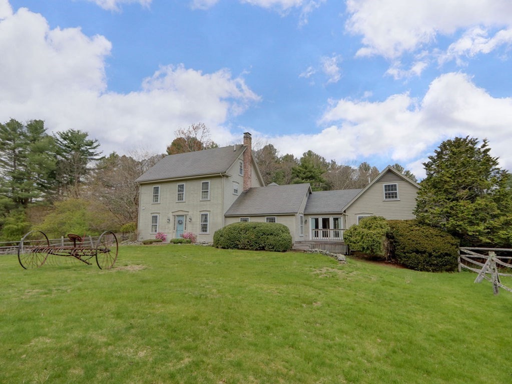 a view of a house with a big yard potted plants and a large tree
