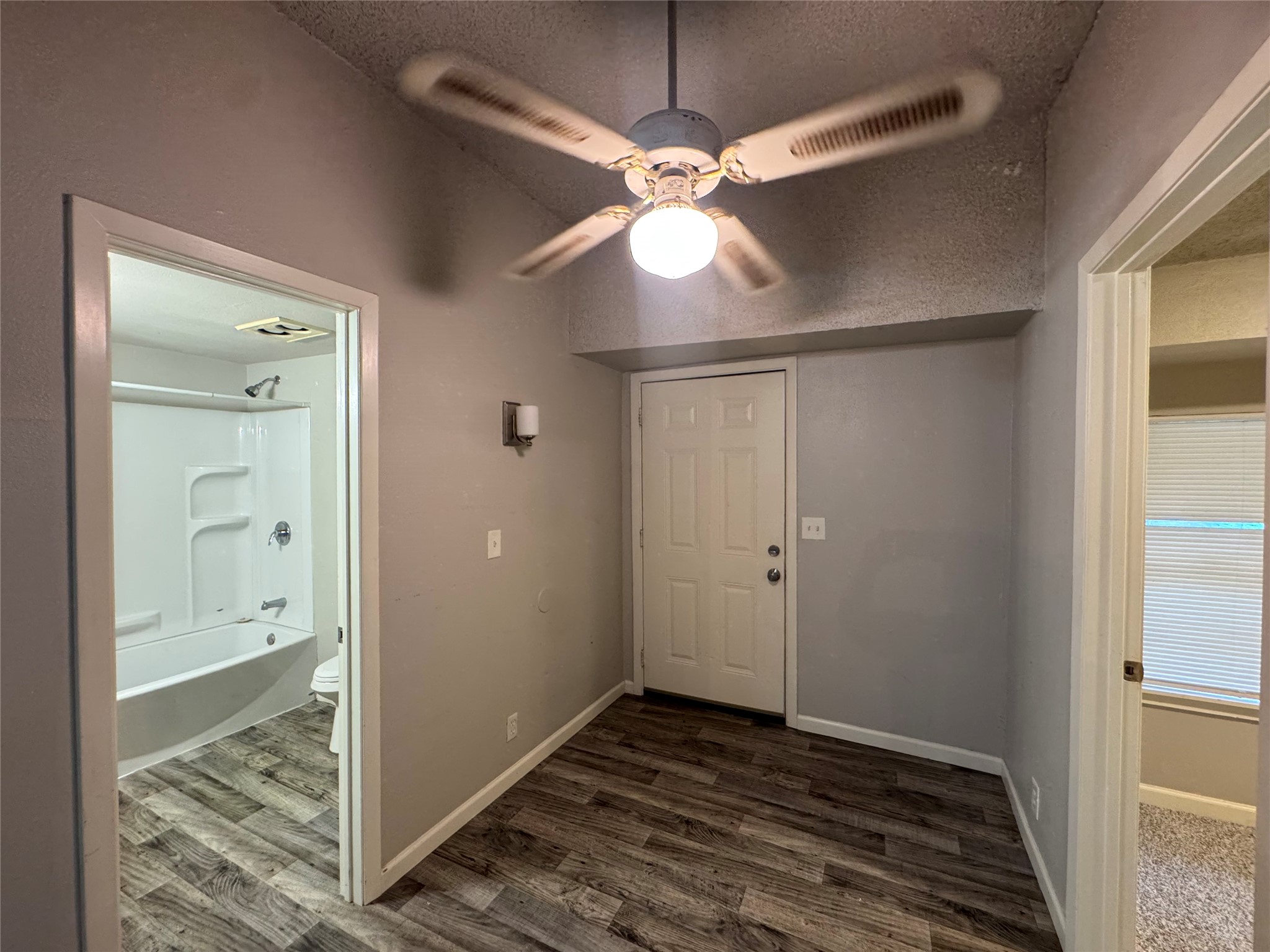 5007 Heflin Lane Austin, TX 78721 - Photo 11 of 25 A compact living space features a convenient ceiling fan and durable flooring, with easy access to the adjacent bathroom.