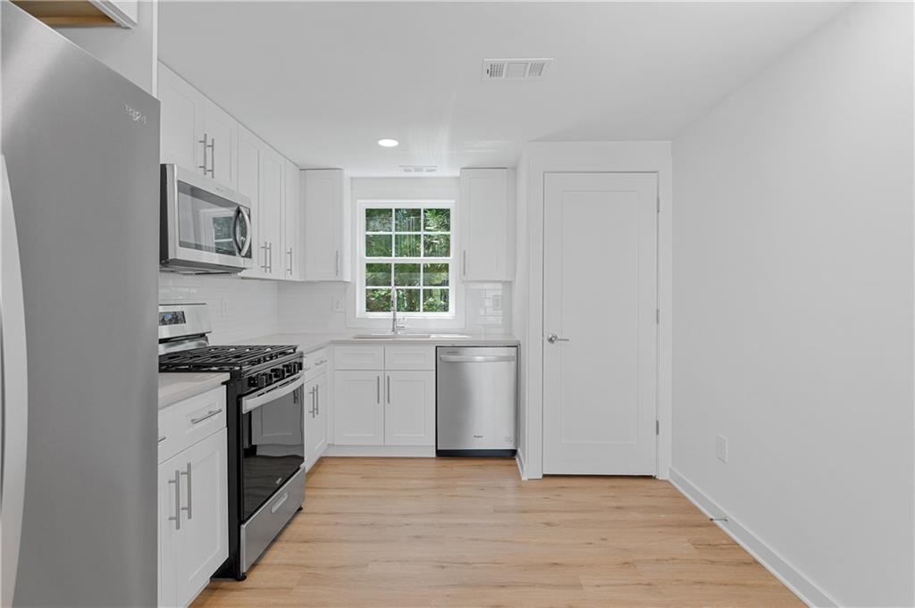 237 Howard Street Northeast, Unit 3 Atlanta, GA 30317 - Photo 7 of 18 a kitchen with a stove a sink and a microwave