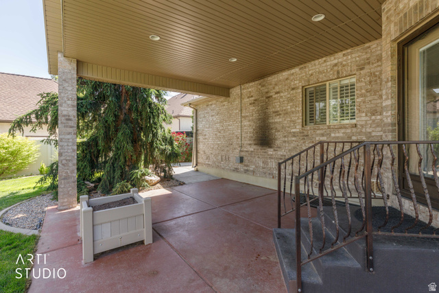 2327 Bluff Ridge Drive Syracuse, UT 84075 - Photo 47 of 66 Covered patio featuring a brick facade, stamped concrete flooring, and an ornamental metal railing