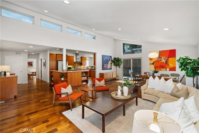 a living room with furniture kitchen view and a large window
