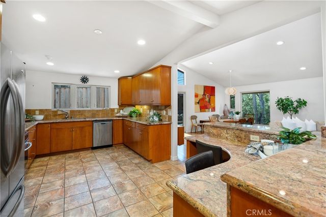 a large kitchen with stainless steel appliances kitchen island granite countertop a large counter top and a stove