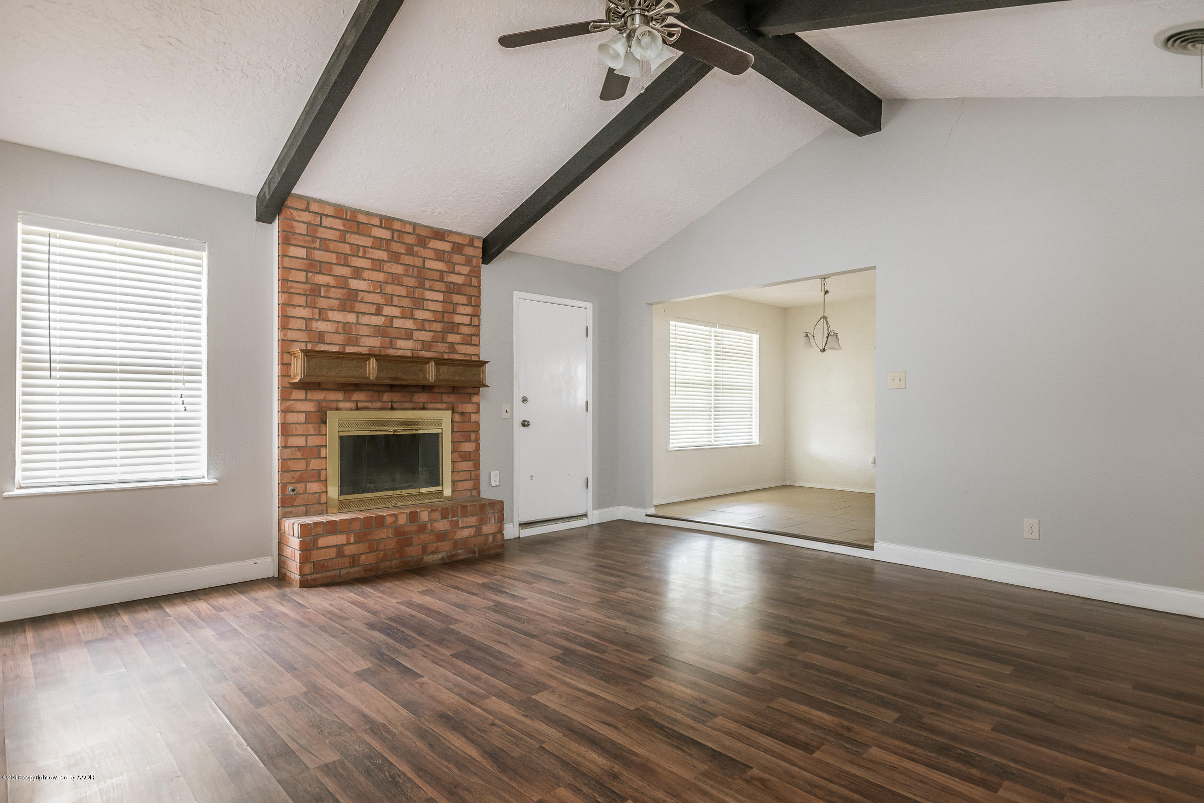 5340 Whitney Lane Amarillo, TX 79110 - Photo 3 of 14 an empty room with wooden floor a fireplace and windows