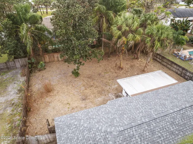 a view of a white house with a small yard and a garden