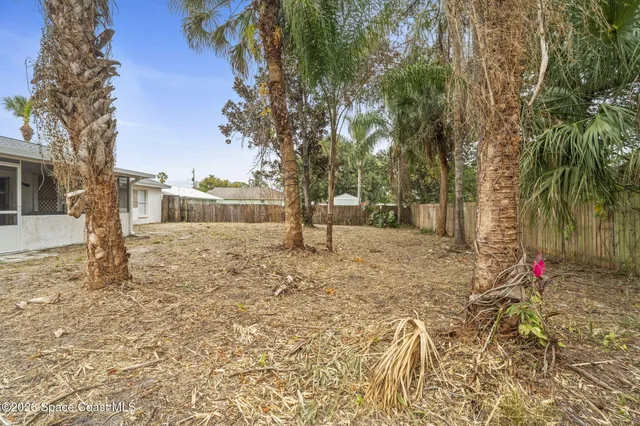 a view of a white house with a yard and palm trees