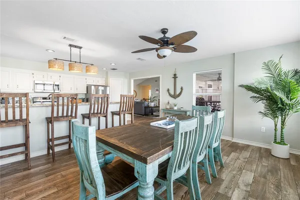 a kitchen with granite countertop a refrigerator a stove a sink a dining table and chairs with wooden floor