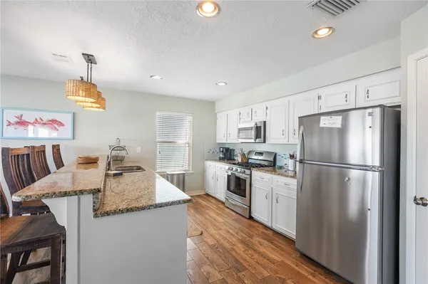 a kitchen with stainless steel appliances granite countertop a sink a stove and a wooden floors