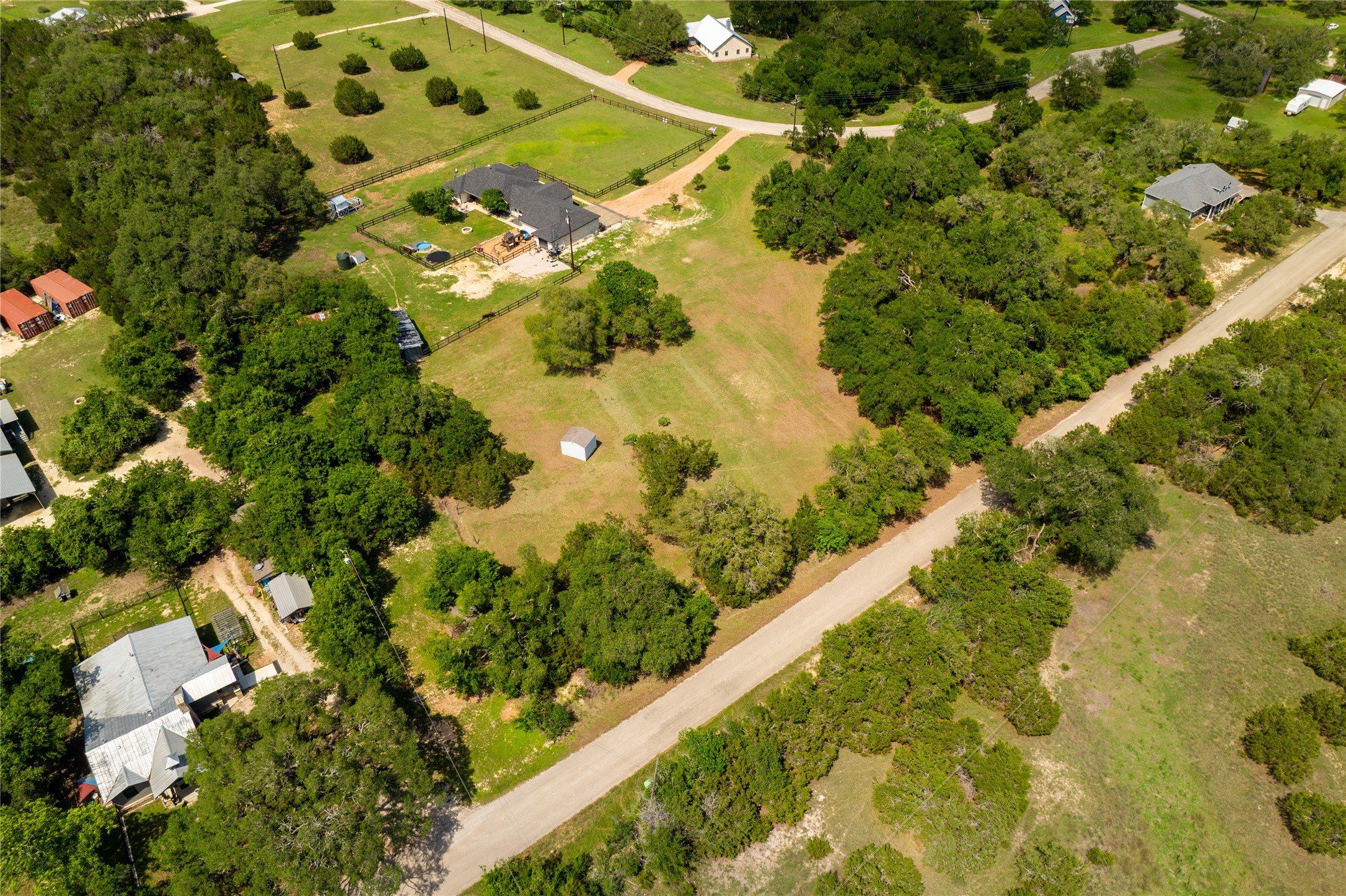 187 Beauchamp Road Dripping Springs, TX 78620 - Photo 12 of 19 Expansive rural property featuring a single-story residence with a dark roof, surrounded by mature trees