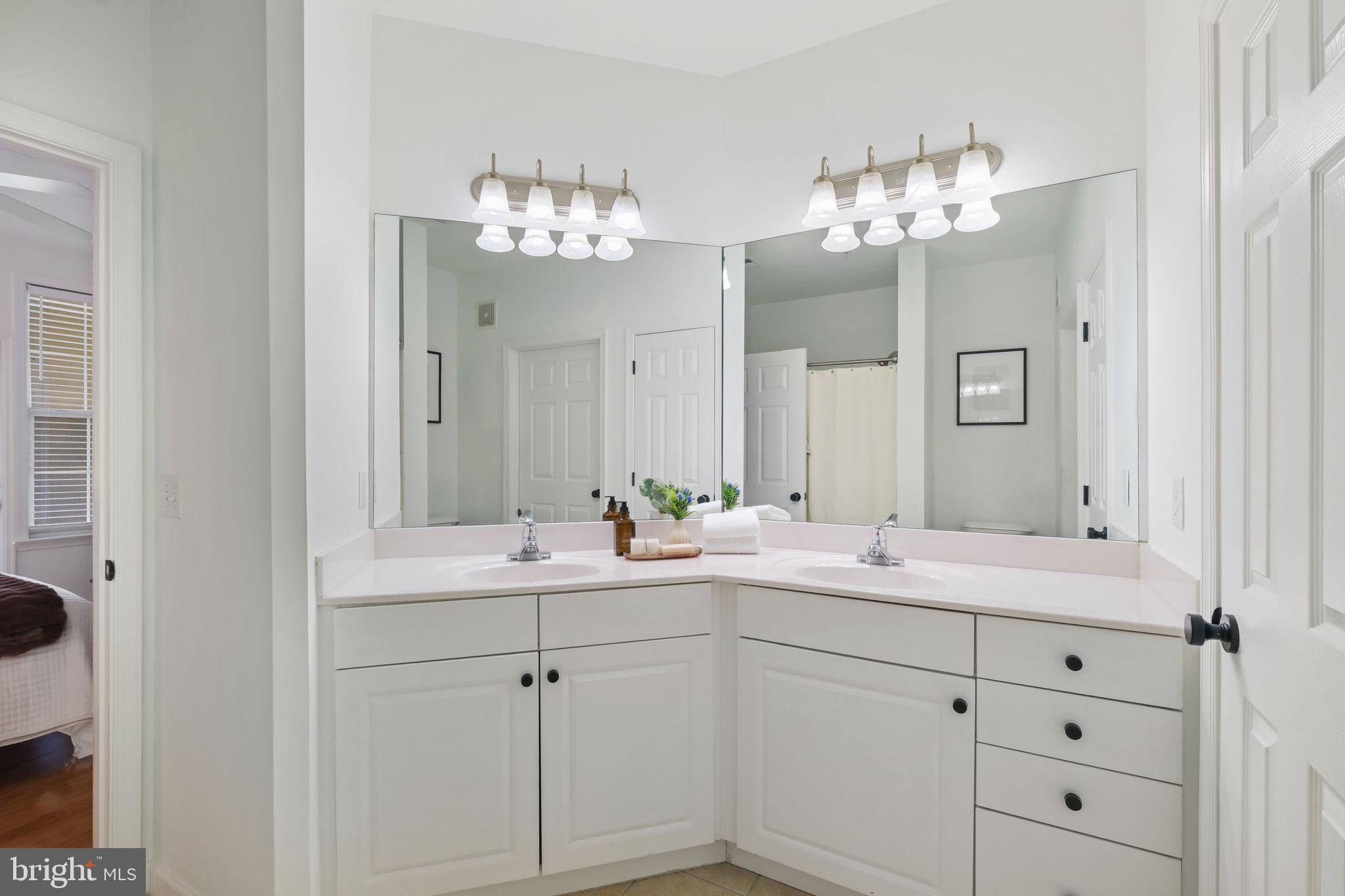 8 Granite Place, Unit 266 Gaithersburg, MD 20878 - Photo 18 of 49 a bathroom with double vanity sinks a vanity a lamp and a mirror