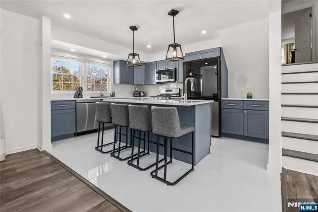 a kitchen with stainless steel appliances granite countertop a sink a stove and a wooden floors