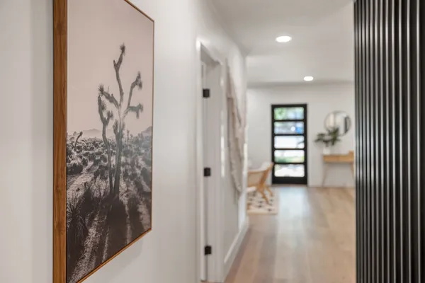 a view of a hallway with wooden floor and a bathroom