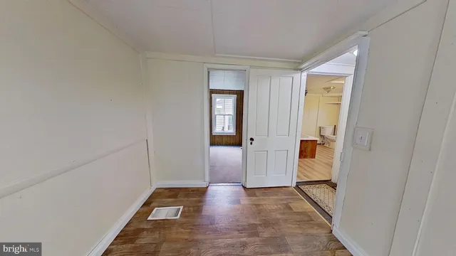 a view of a hallway with wooden floor and a bathroom