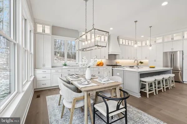 a kitchen with a dining table chairs and large windows