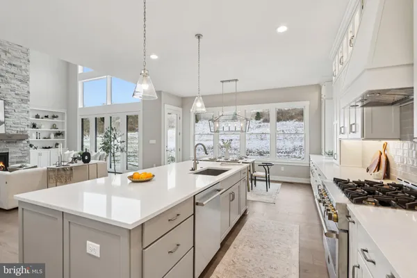 a kitchen with a stove a sink a refrigerator and chairs