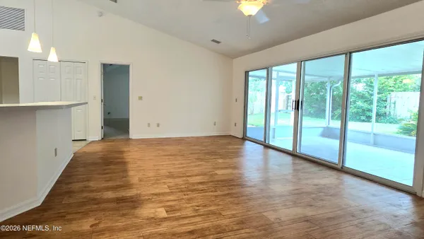 a view of an empty room with a window and wooden floor