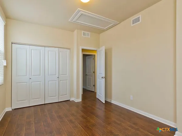 a view of an empty room with wooden floor and closet