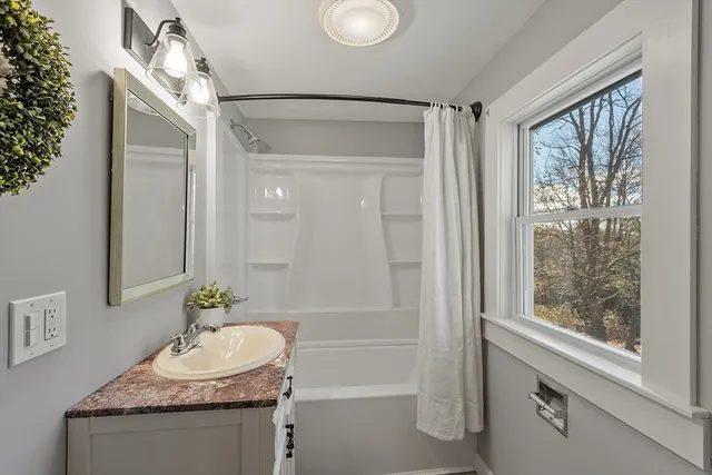 a bathroom with a granite countertop sink a mirror and a shower