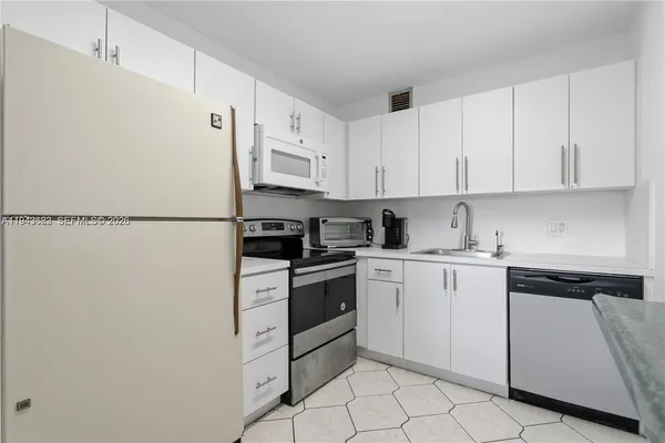 a kitchen with white cabinets and white appliances