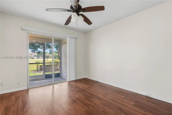 an empty room with wooden floor fan and windows