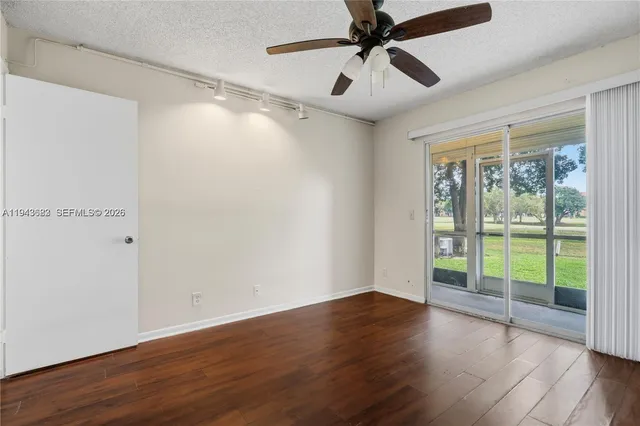 an empty room with wooden floor fan and windows