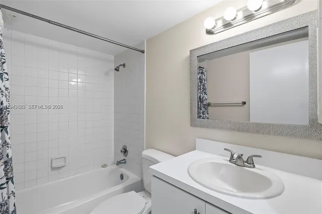 a white bath tub sitting next to a white sink and a mirror