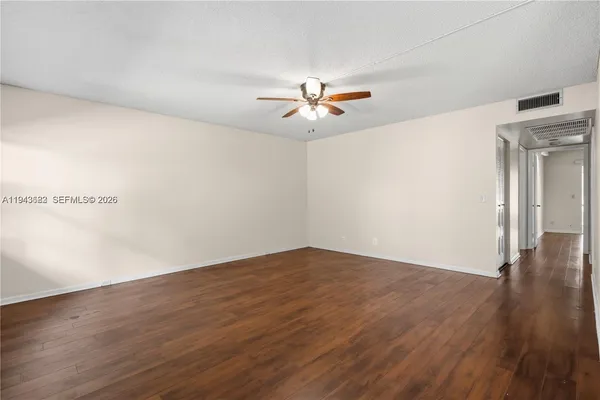 a view of a big room with wooden floor and a chandelier fan