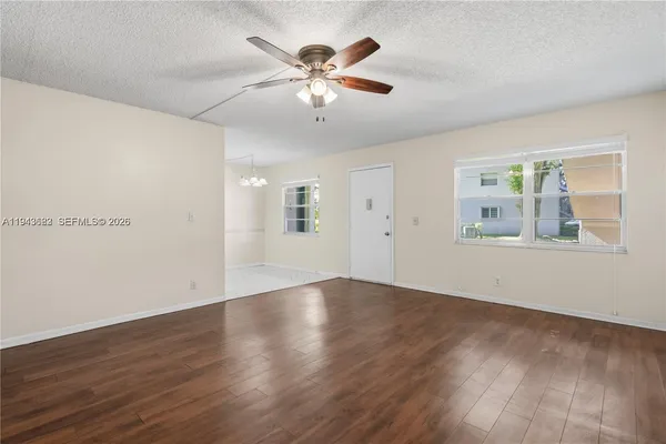 an empty room with wooden floor chandelier fan and windows