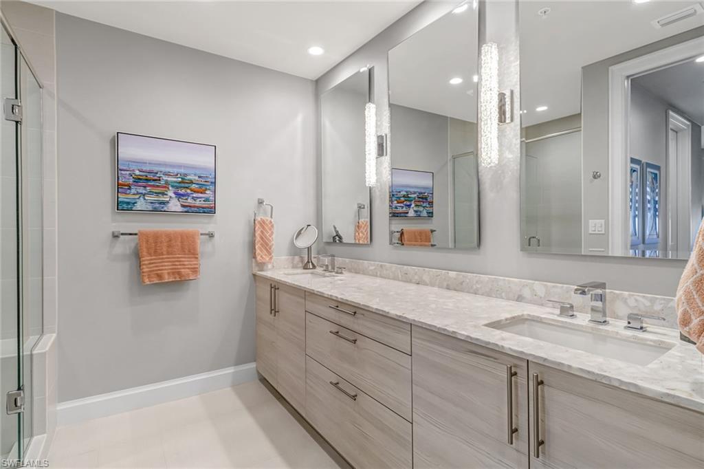 1111 Central Avenue, Unit 203 Naples, FL 34102 - Photo 12 of 19 a bathroom with a granite countertop sink a large mirror a shower and a bathtub