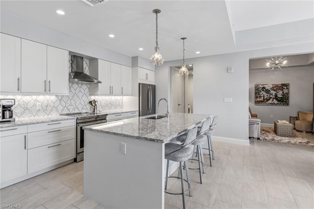 1111 Central Avenue, Unit 203 Naples, FL 34102 - Photo 2 of 19 a kitchen with kitchen island granite countertop a center island a sink stainless steel appliances and cabinets