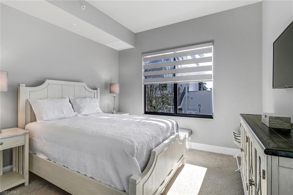 1111 Central Avenue, Unit 203 Naples, FL 34102 - Photo 9 of 19 a bedroom with a bed and a tv on the dresser