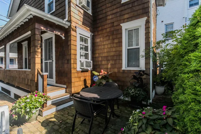 a backyard of a house with table and chairs with potted plants