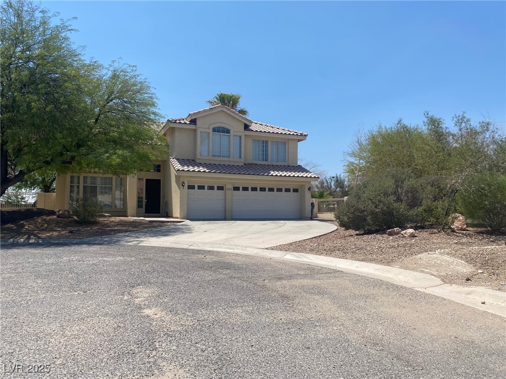 View of front of property with a garage, concrete driveway, a tiled roof, and stucco siding
