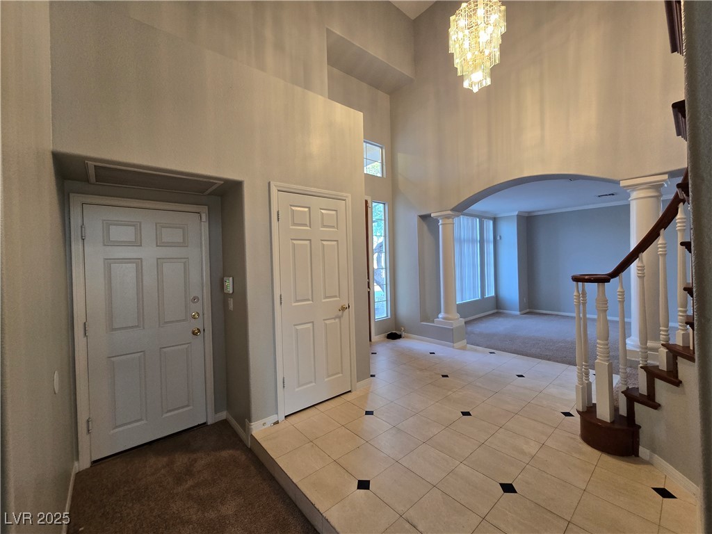Undisclosed Address Las Vegas, NV 89149 - Photo 4 of 34 Entryway with arched walkways, tile patterned flooring, carpet flooring, a high ceiling, and a chandelier
