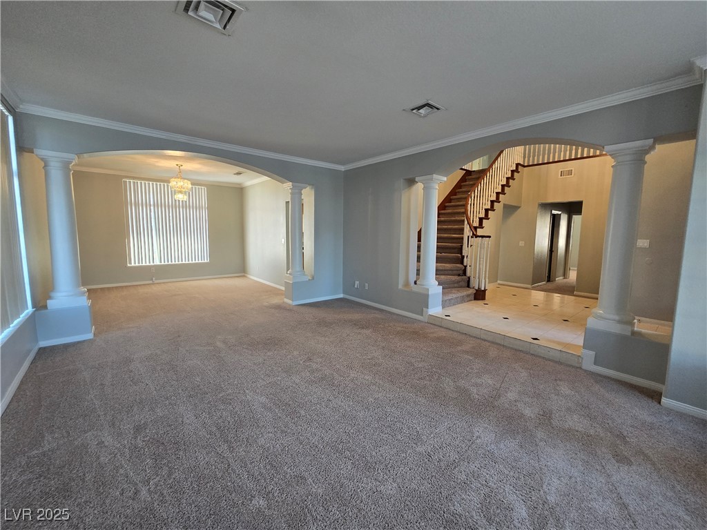 Undisclosed Address Las Vegas, NV 89149 - Photo 5 of 34 Unfurnished living room featuring crown molding, arched walkways, carpet flooring, and a chandelier