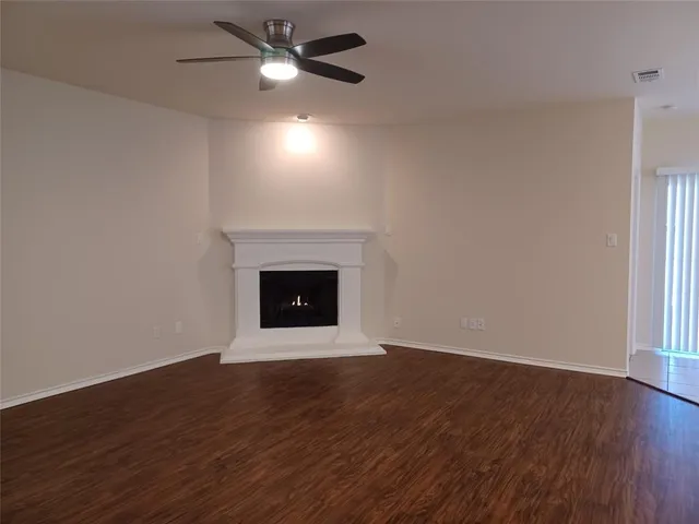 a view of an empty room with wooden floor and a fireplace