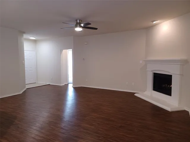 a view of an empty room with wooden floor fireplace and a window