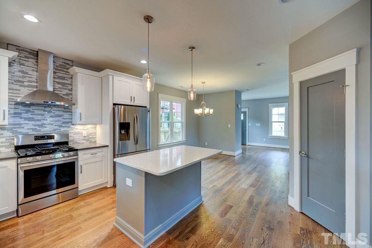 1416 East Jones Street Raleigh, NC 27610 - Photo 7 of 30 a kitchen with kitchen island a stove a sink a refrigerator and a wooden floor