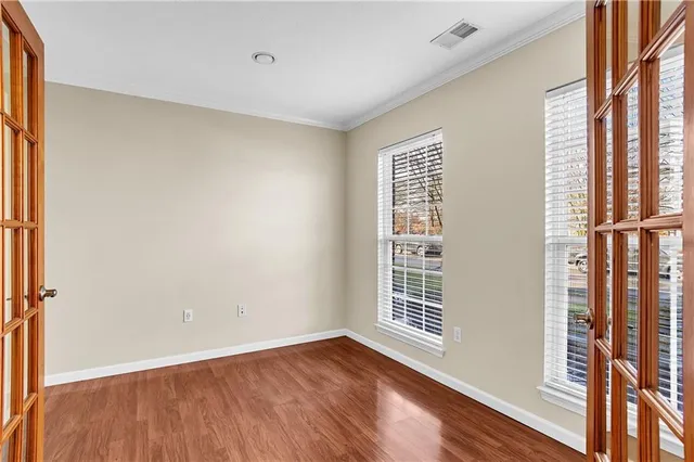 a view of an empty room with wooden floor and a window
