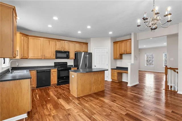 a kitchen with kitchen island granite countertop a stove top oven a sink dishwasher a dining table and chairs with wooden floor