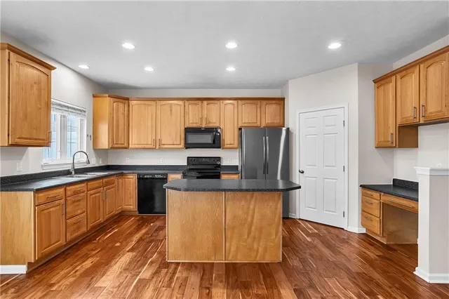 a kitchen with stainless steel appliances granite countertop a refrigerator a stove top oven a sink and dishwasher with wooden floor