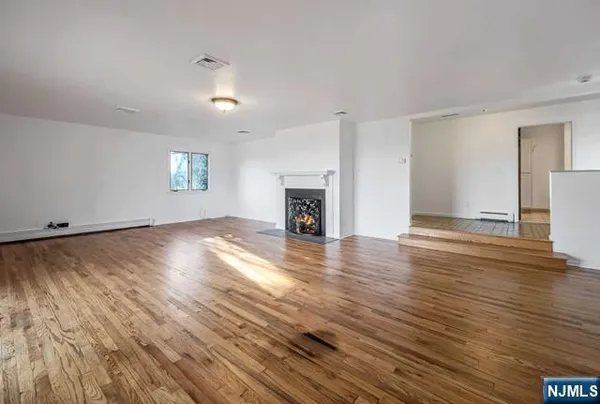 an empty room with wooden floor fireplace and windows