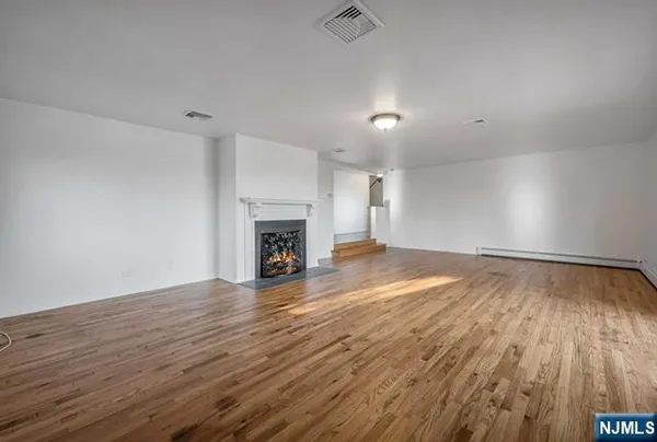 an empty room with wooden floor and a fireplace