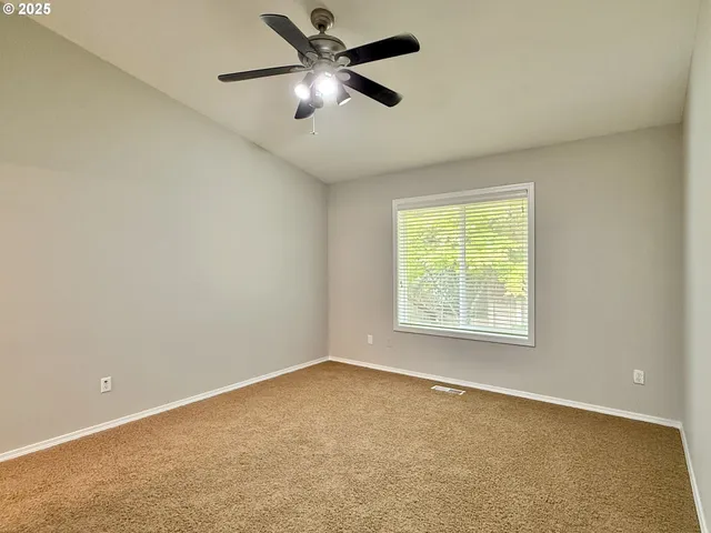 an empty room with a window and a fan