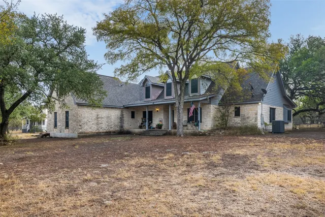 a front view of a house with a dirt yard and a large tree